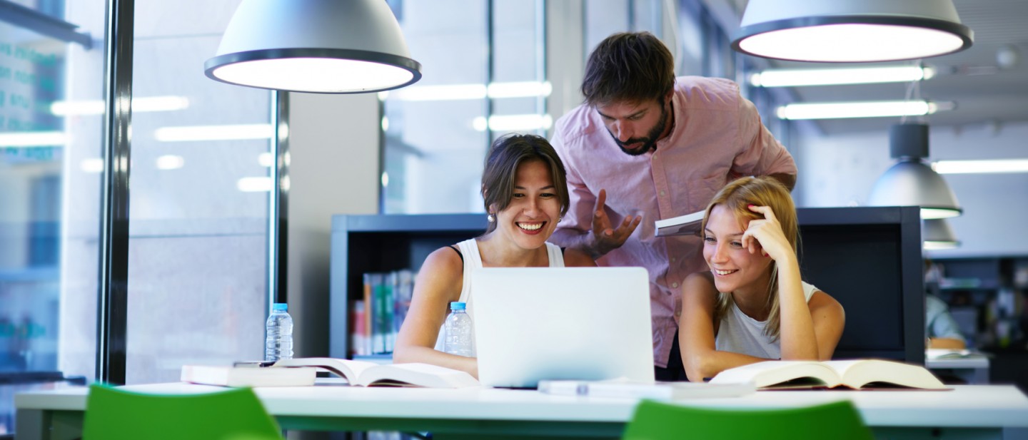 Students reviewing a computer in the library