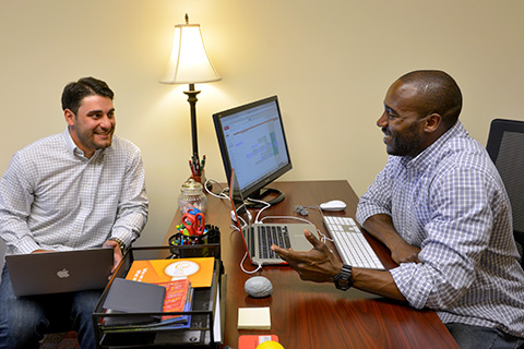 Two men speaking at a desk