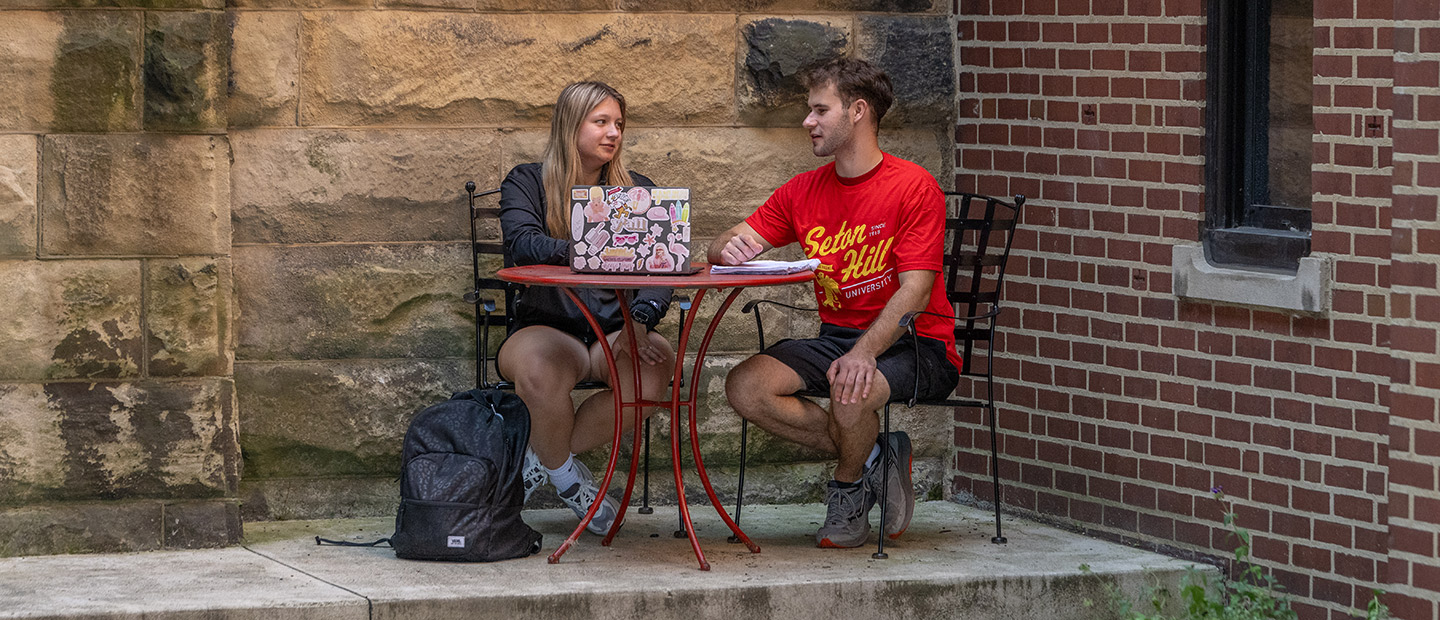 Students working at a table in a courtyard