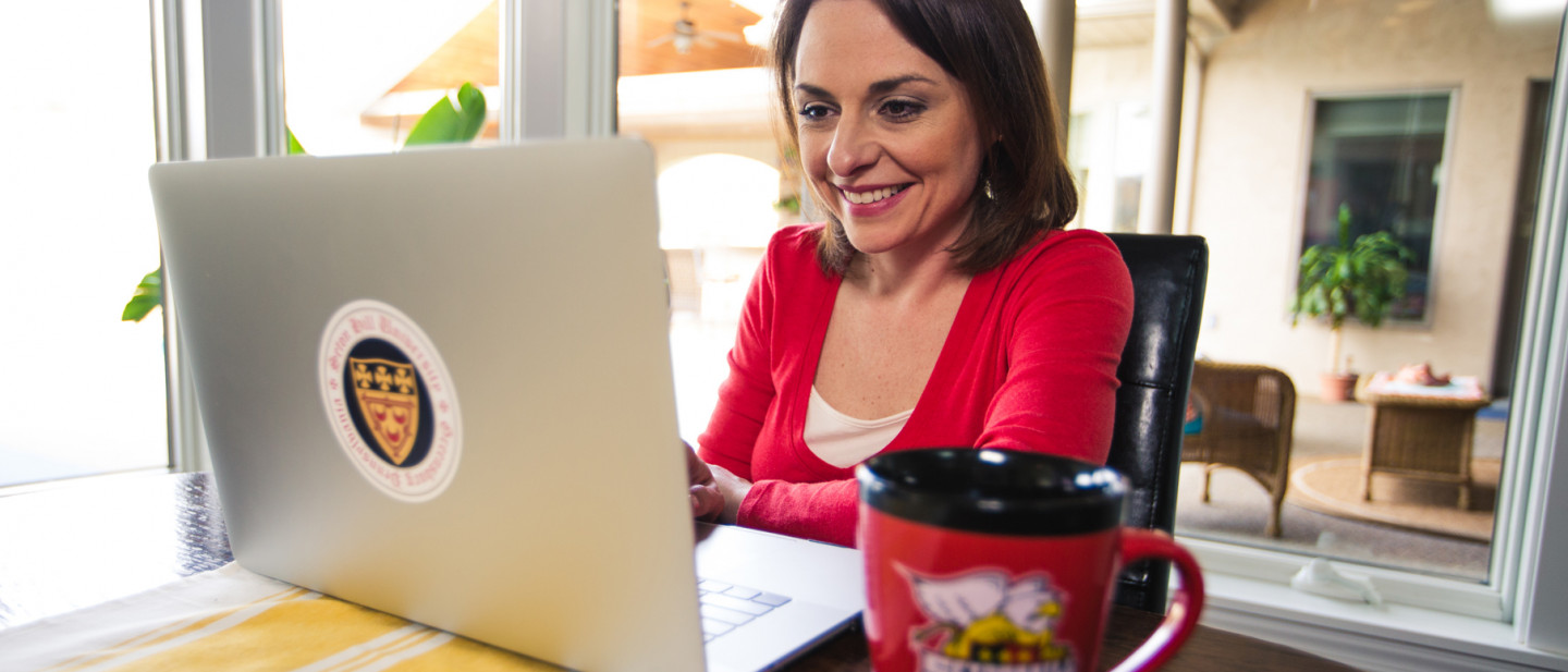 Adult student working on laptop in kitchen