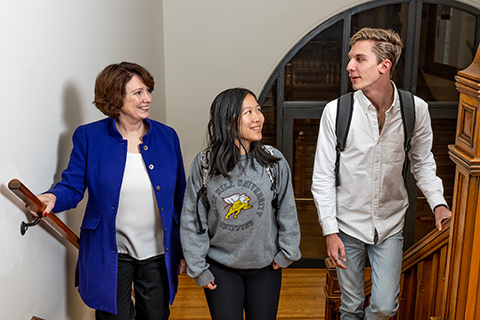 President Mary Finger walks up stairs with two students