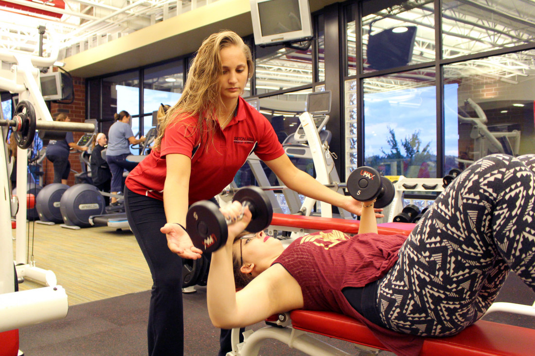 An Exercise Science student works with a fellow student in the McKenna Fitness Center.