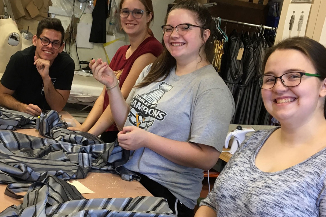 Theatre and Dance Department students in the costume shop sewing snaps of the prison smocks for the production of Chicago.