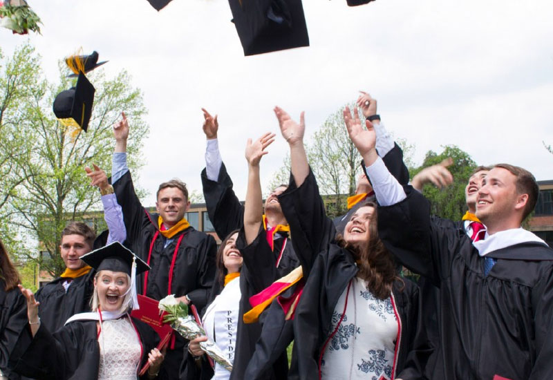 seton hill university graduates tossing caps into the air.